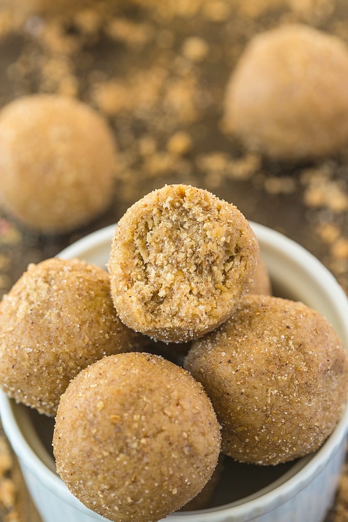 A white bowl filled with no bake gingerbread energy bites with the top one showing a textured internal bite!