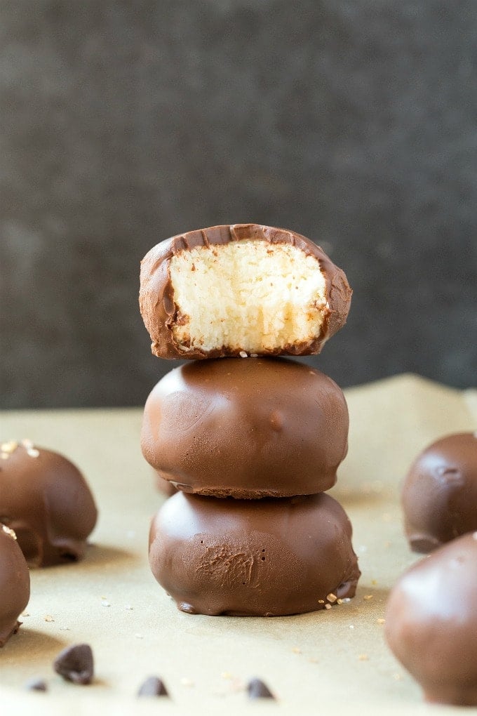 A stack of no bake chocolate coconut balls with the top one showing an interior shot. 
