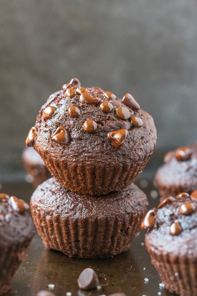 Several flourless chocolate muffins stacked covered in melted chocolate chips