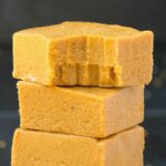 3 keto peanut butter no bake bars stacked on top of one another with the top bar with a bite mark out of it.