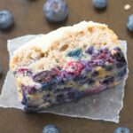 A thick slice of flourless keto blueberry breakfast cake topped with a thick vanilla frosting, which is healthy!
