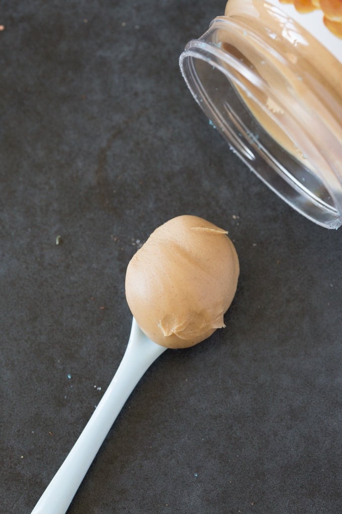 A spoonful of peanut butter, with the jar in the background