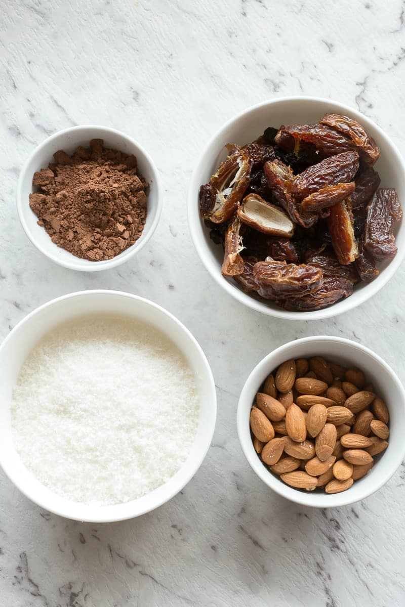 cocoa powder, pitted dates, shredded coconut and almonds in bowls