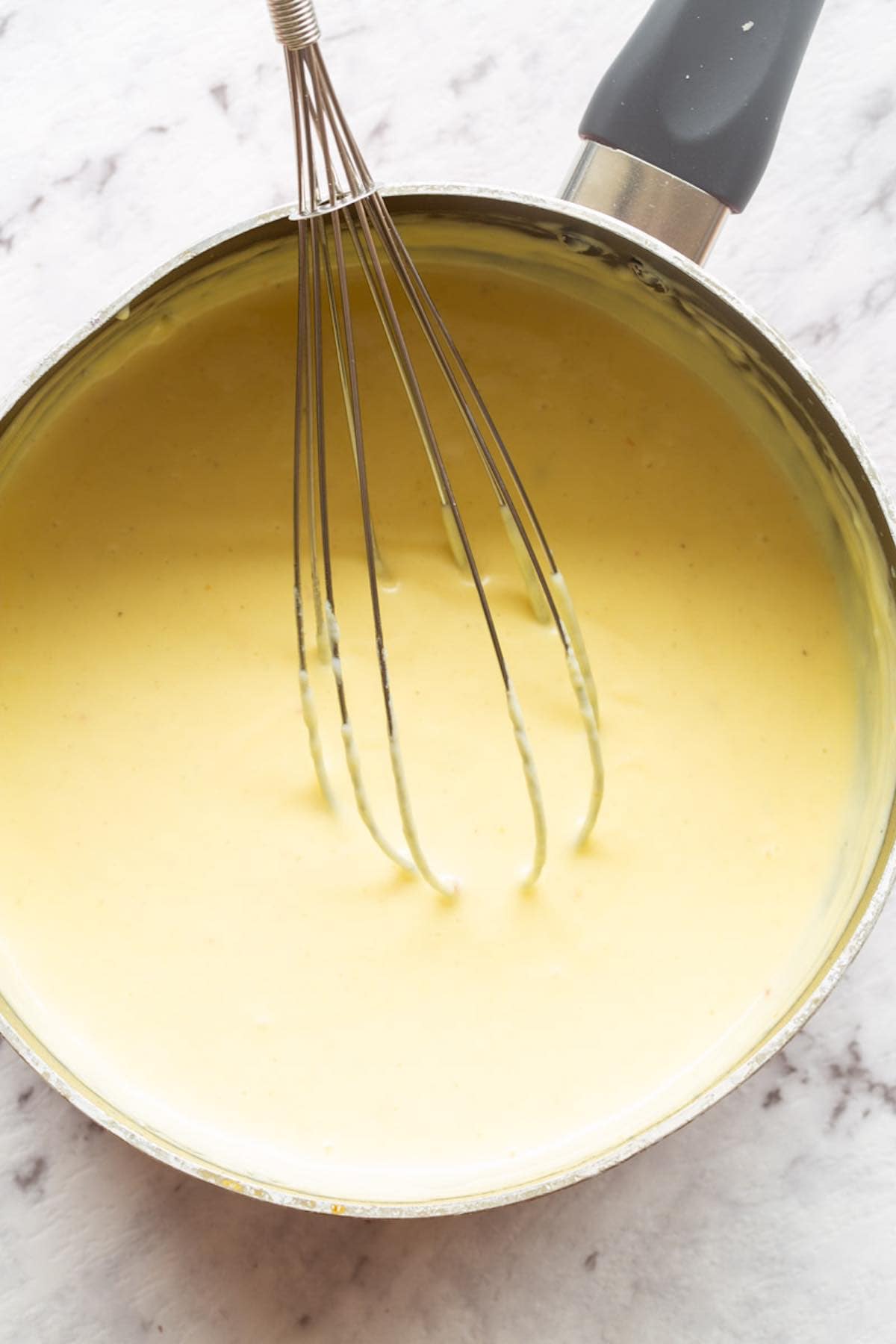whisking keto cheese sauce in a saucepan.