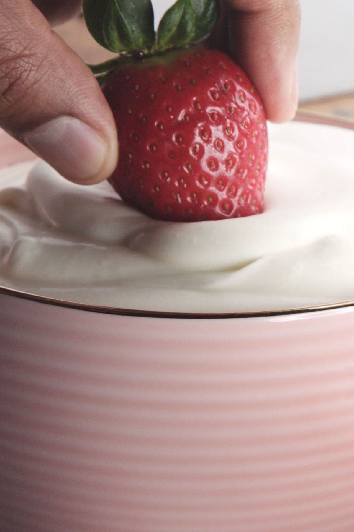 keto fruit dip in a bowl with a fresh strawberry dunked in.