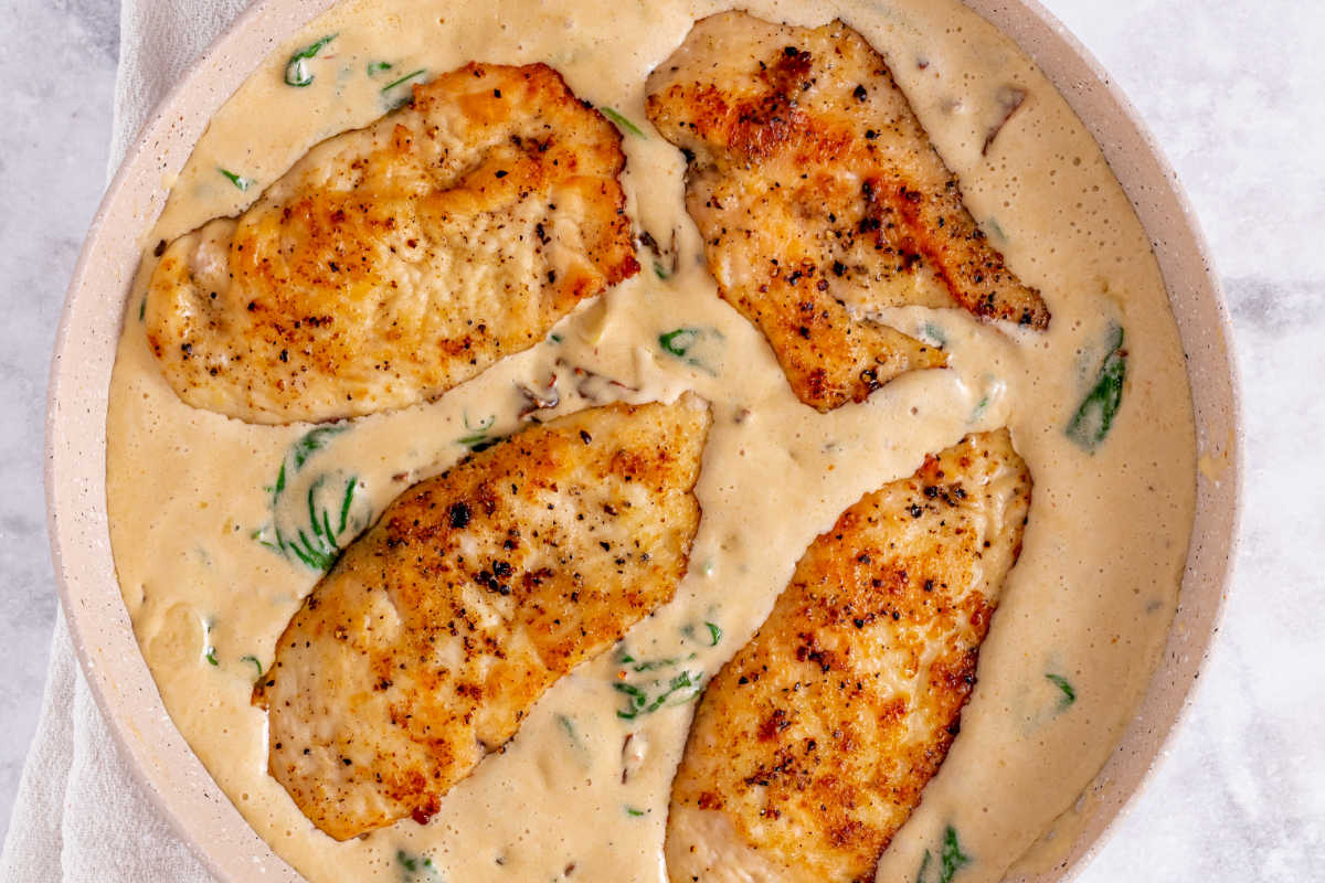 chicken in a pan with creamy sauce.