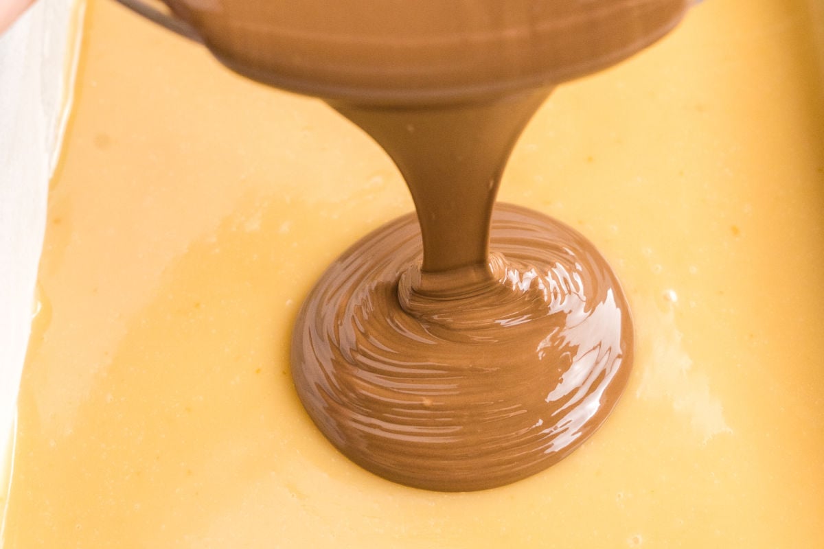 pouring melted chocolate on caramel.
