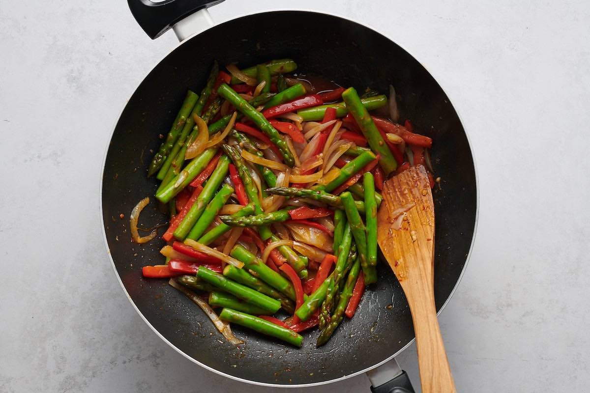 asparagus, bell peppers, and onions in a pan.