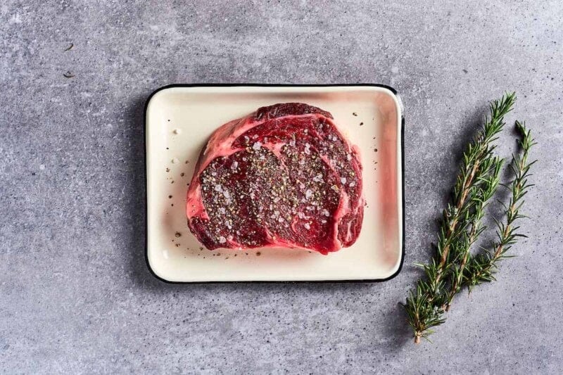 raw steak seasoned with salt and pepper.