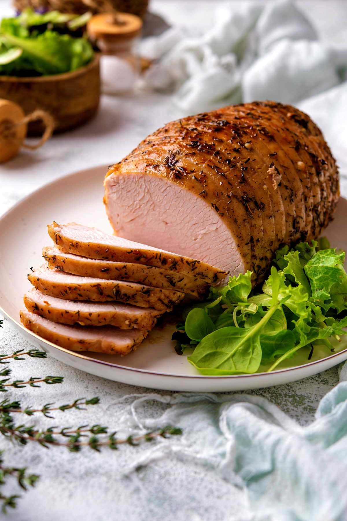 boneless turkey breast on a white plate with salad.