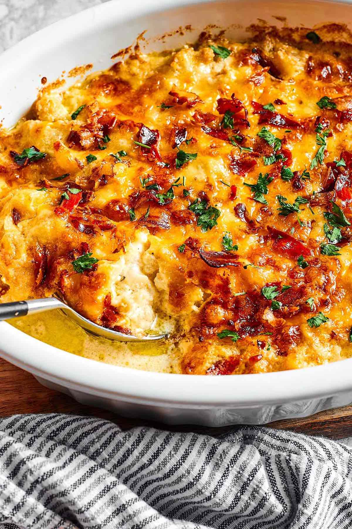 cauliflower casserole with bacon, herbs, and melted cheese on top.