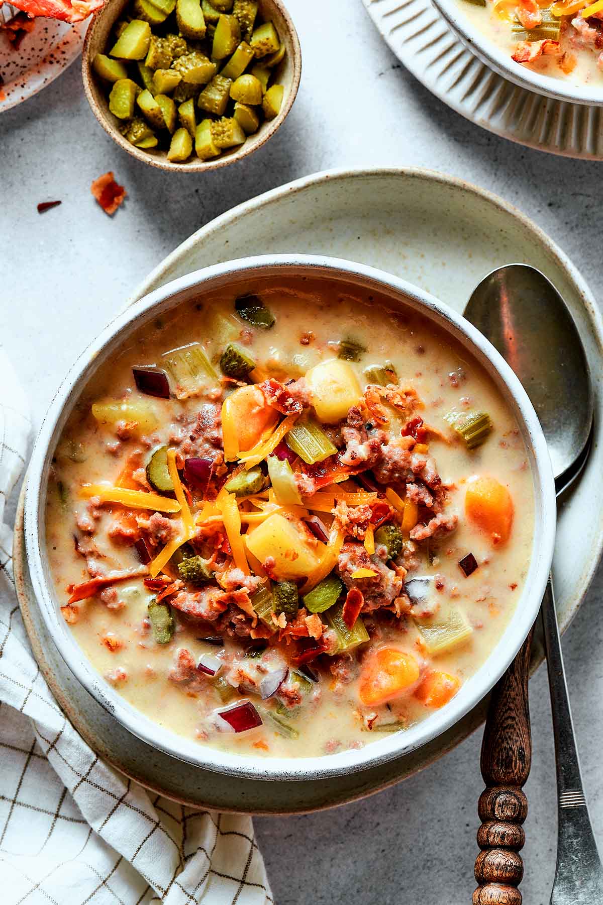 bacon cheeseburger soup in bowls with a soup spoon.