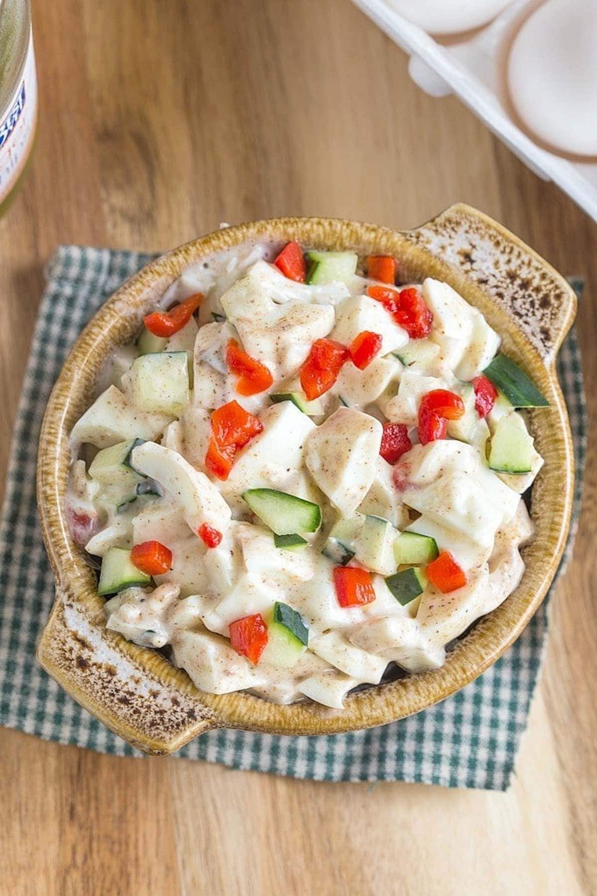 egg white salad with roasted red peppers and cucumber slices on top.