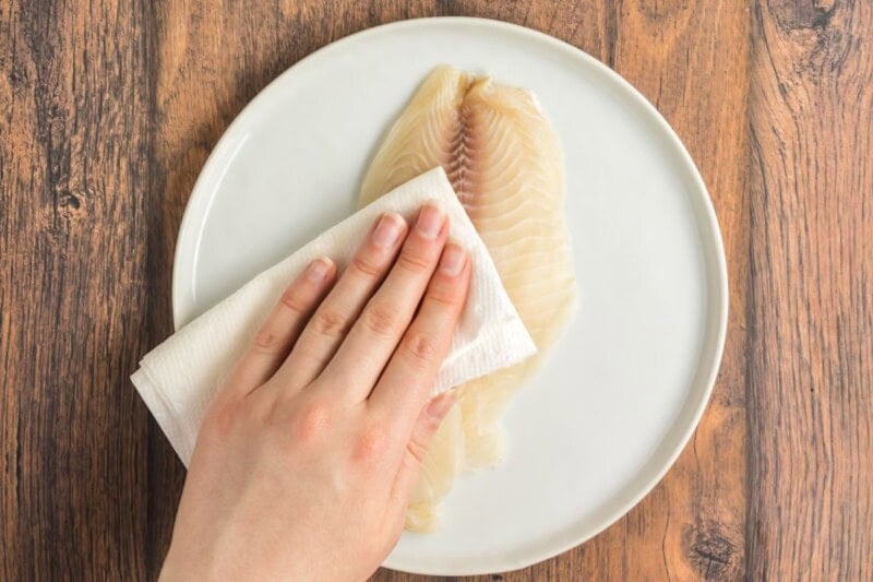 patting dry raw tilapia.