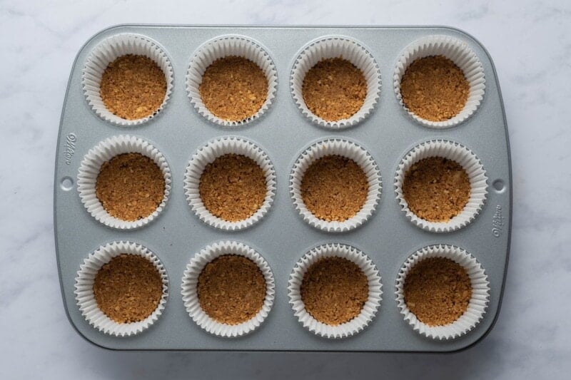 graham cracker cheesecake crust in a muffin tin.