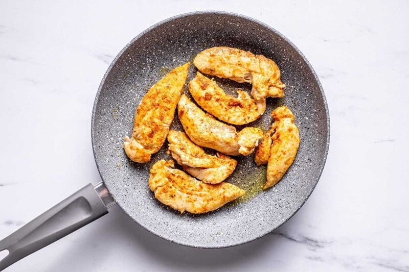 chicken tenderloins frying in pan.