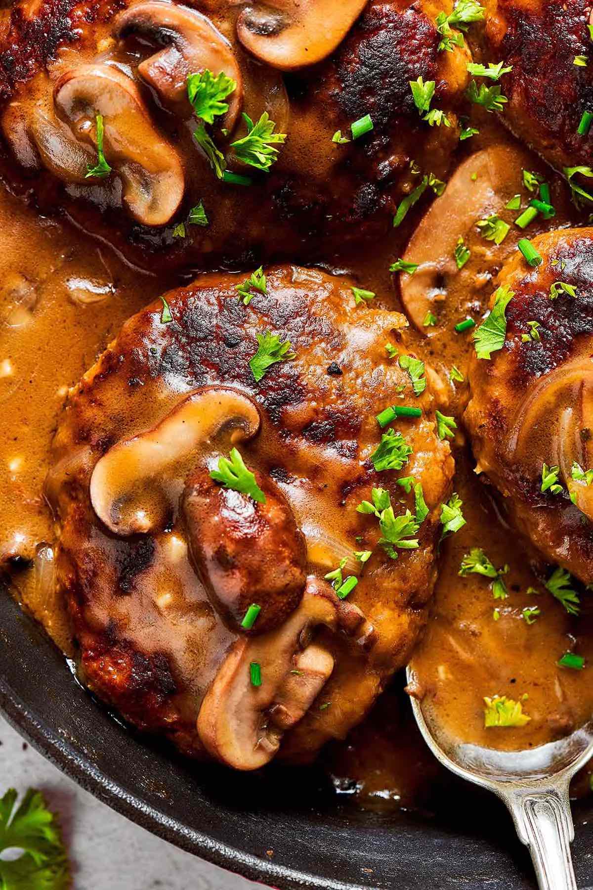 homemade salisbury steak with fresh herbs on top.