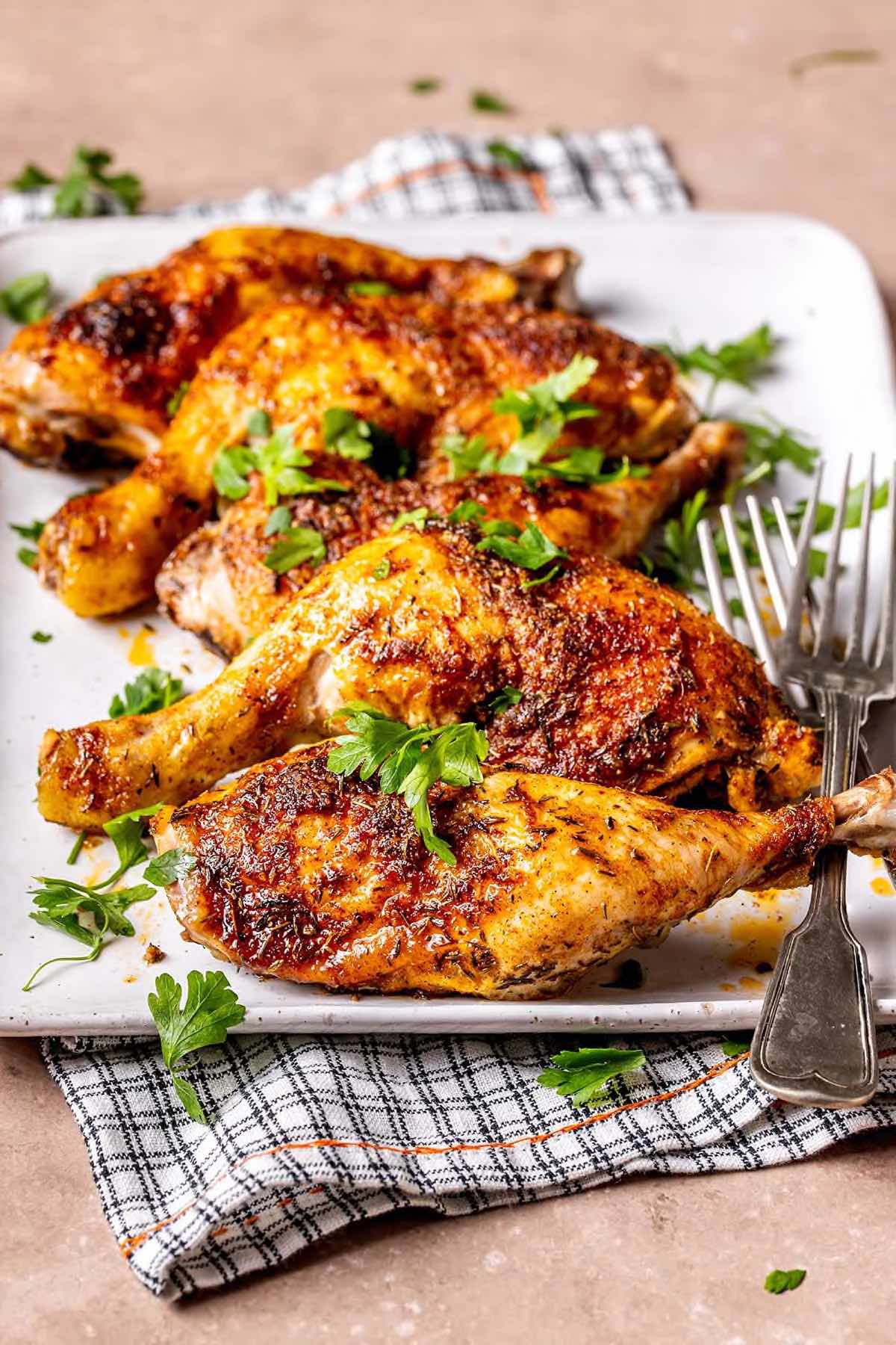 crispy baked chicken leg quarters with parsley on top.