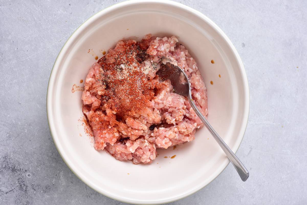 ground chicken with spices in a mixing bowl.