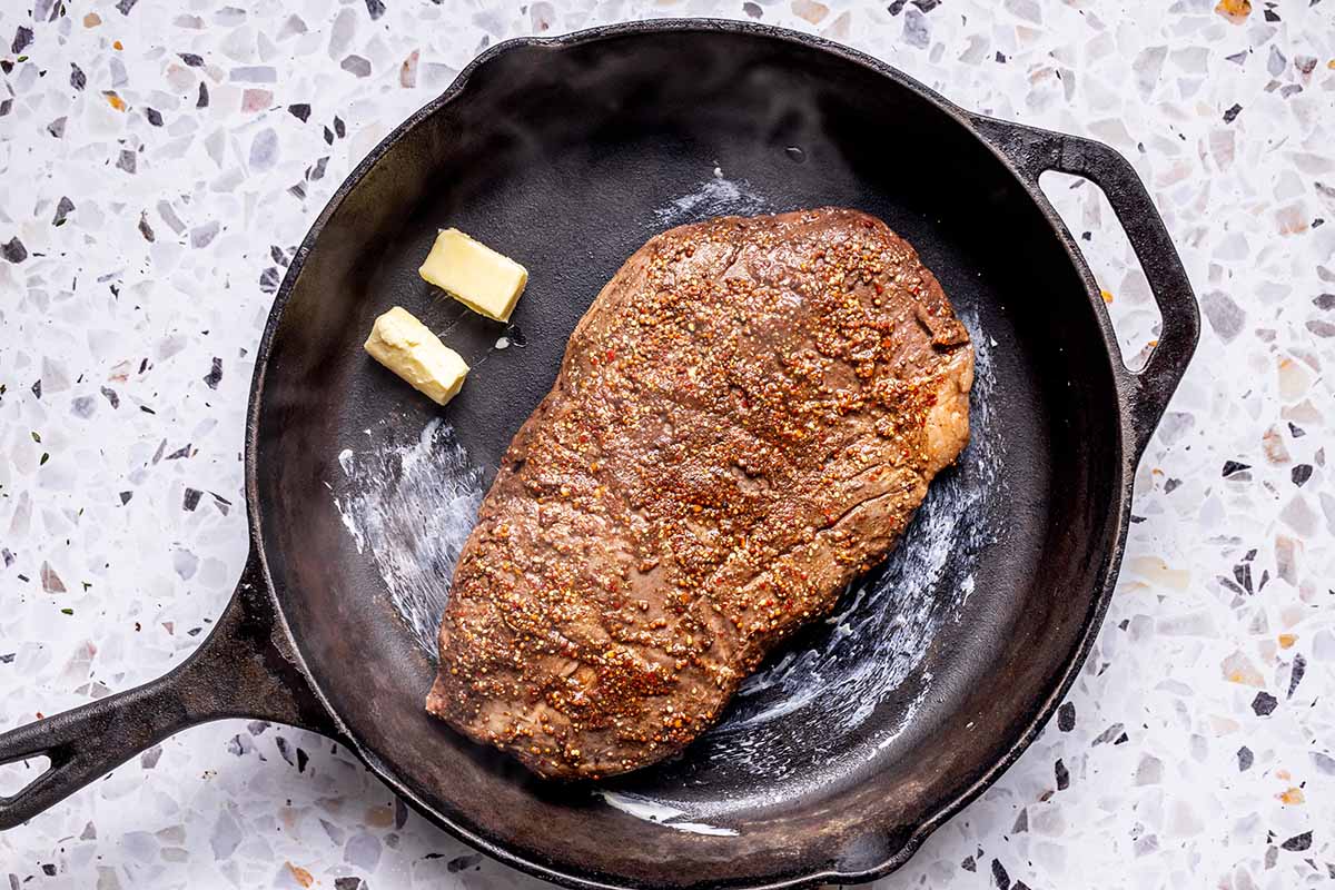 flank steak on skillet with butter.