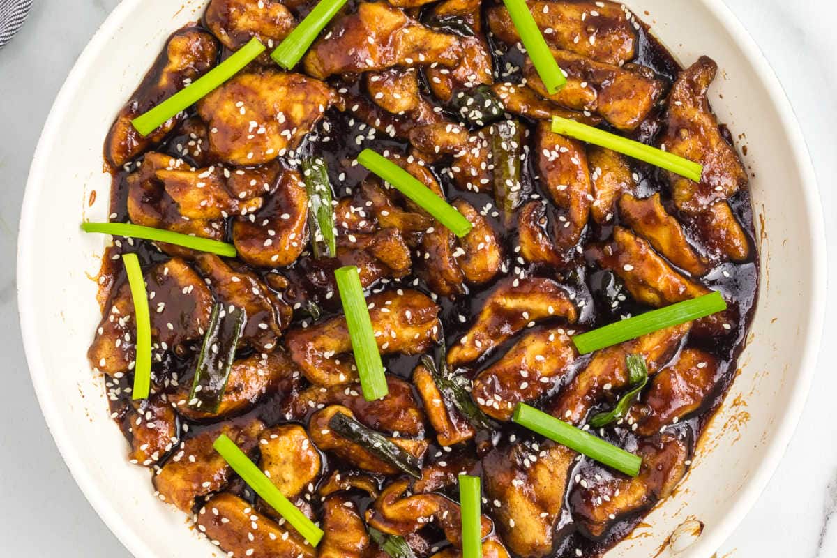 mongolian chicken in wok with green vegetables.