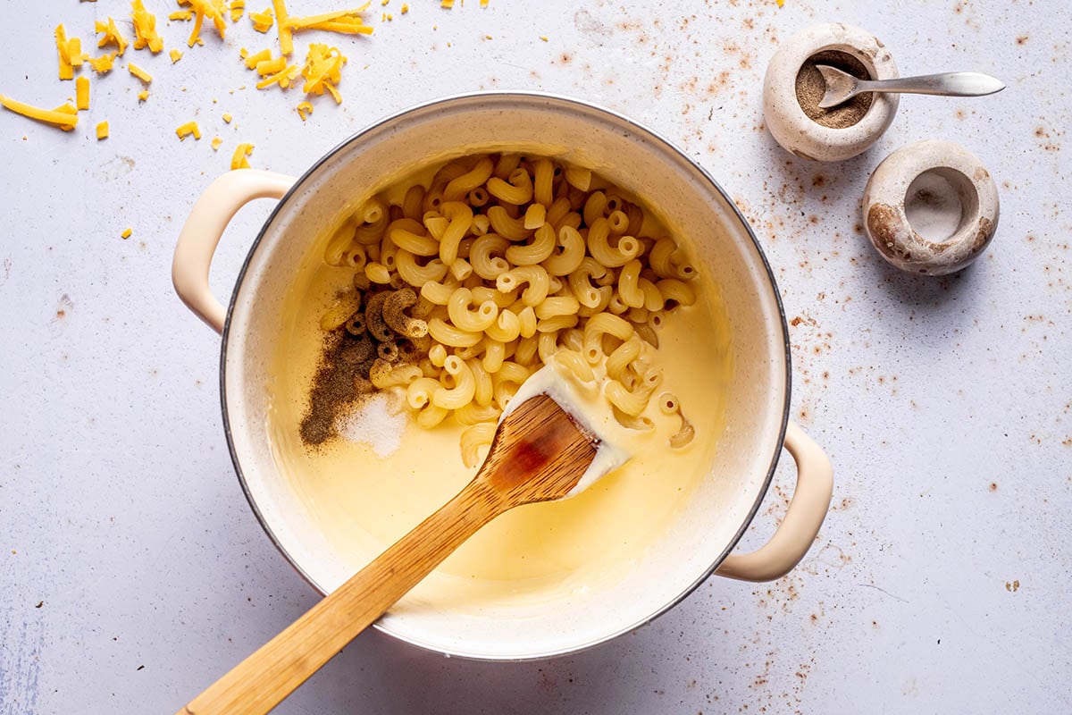 combining macaroni and cheese sauce in pot.