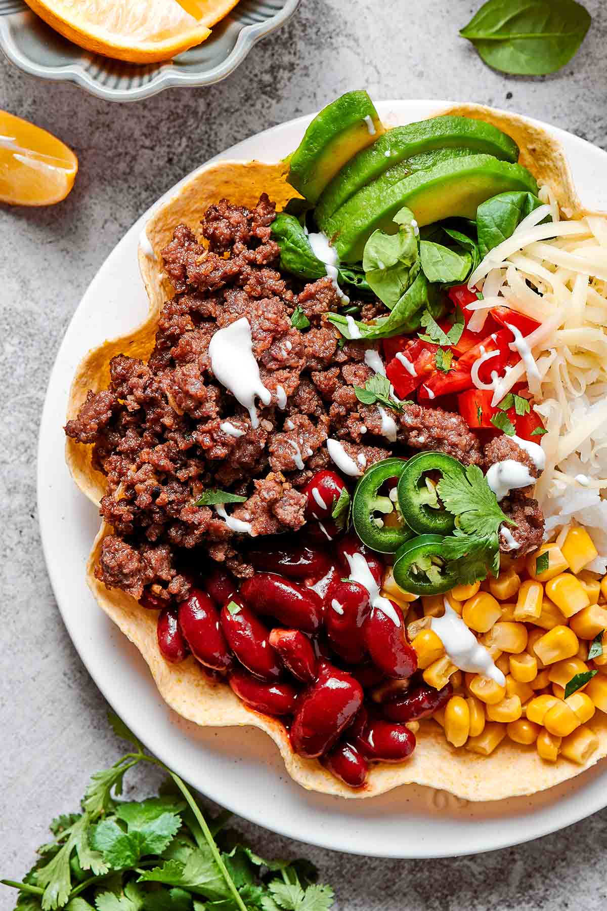 taco bowl filled with kidney beans, corn, avocado, shredded cheese, and sour cream.