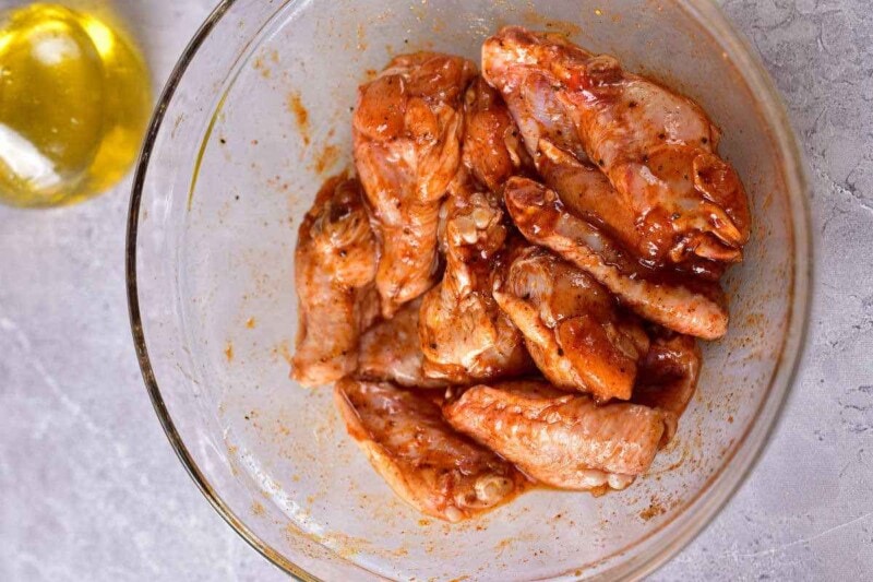 raw chicken wings with seasonings in a bowl.