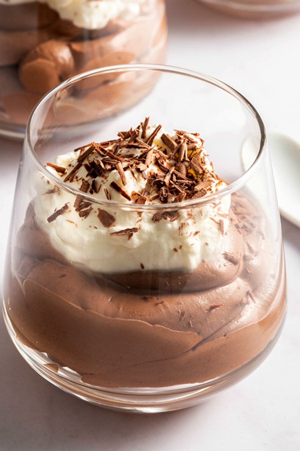 keto chocolate mousse in a glass with whipped cream and sugar free chocolate shavings on top. 