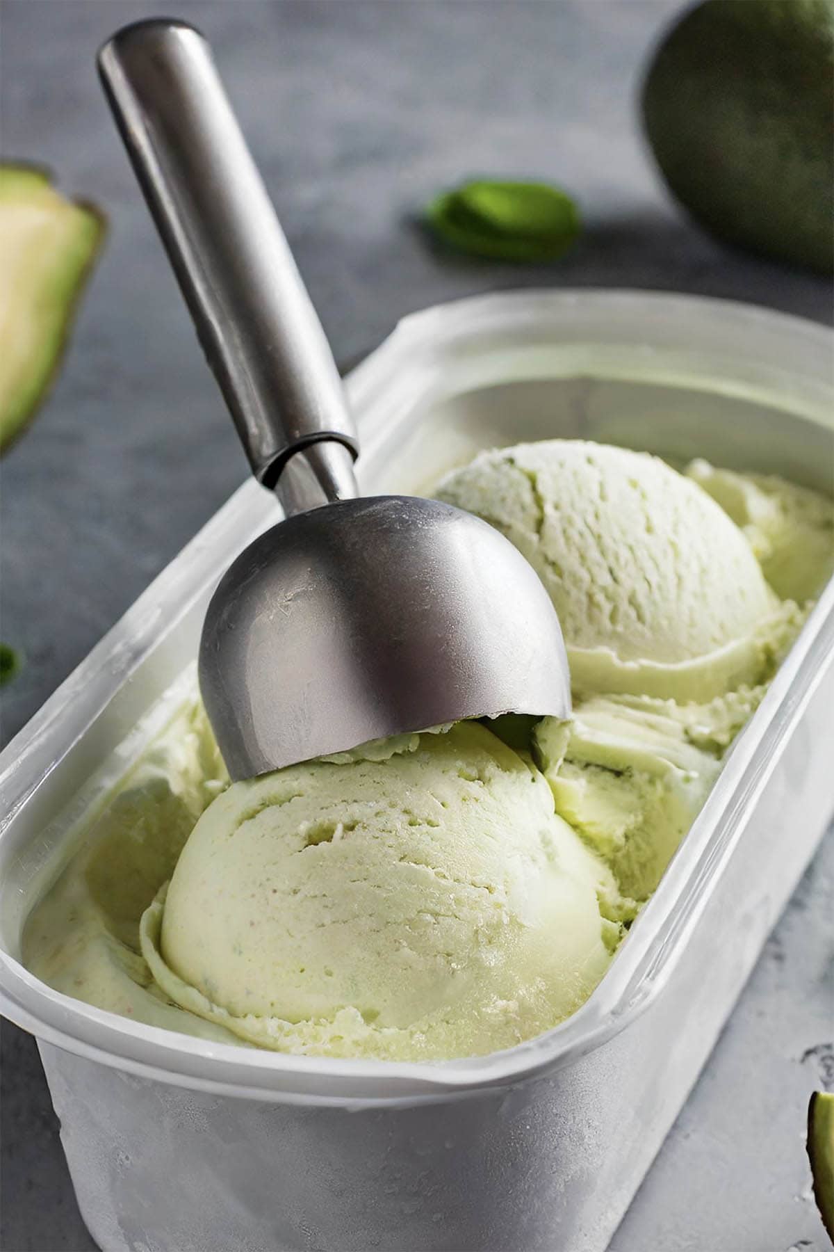 avocado ice cream in ice cream tin with scoop coming out.