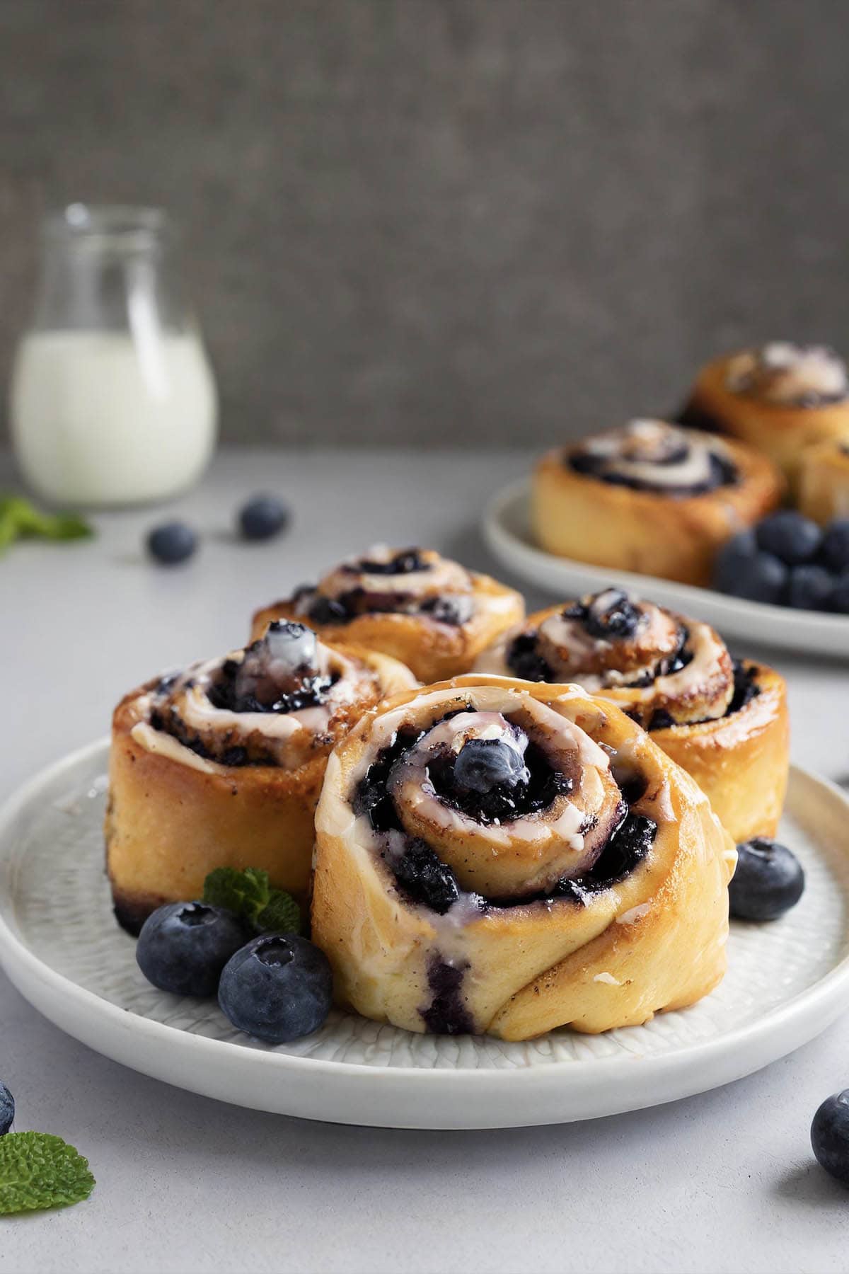 blueberry cinnamon rolls on a white plate.