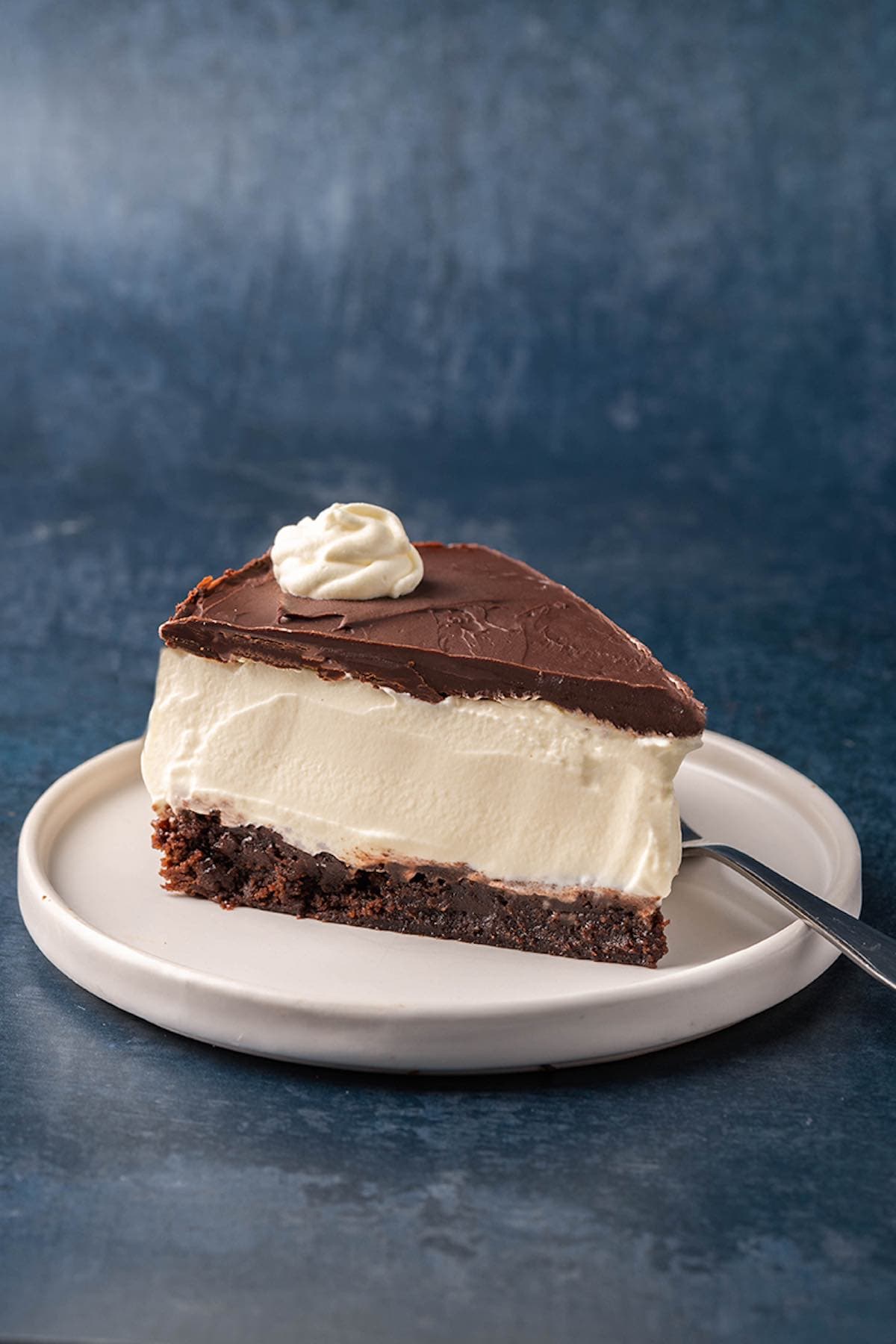 slice of brownie cheesecake with whipped cream on top.