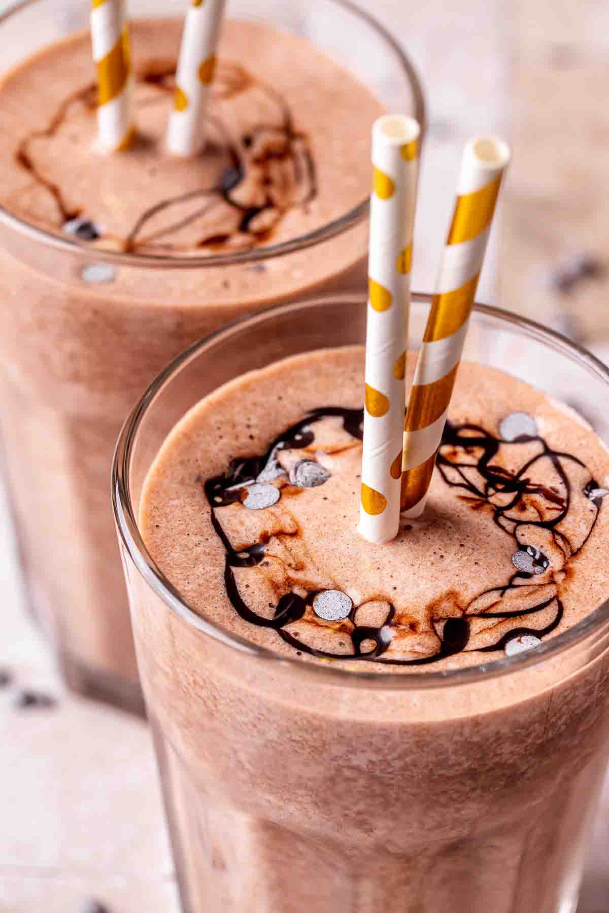 chocolate protein shakes in a glass with a straw.
