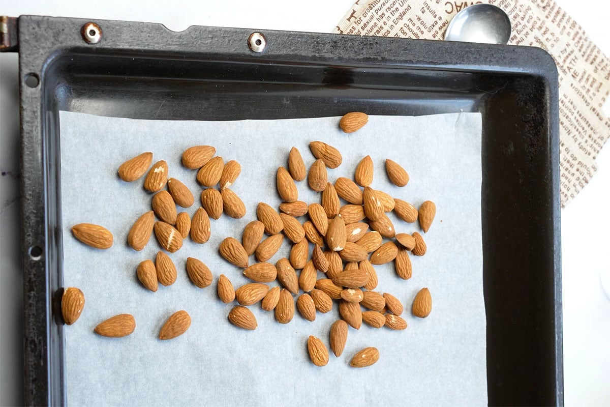 raw unsalted almonds on a lined baking sheet.