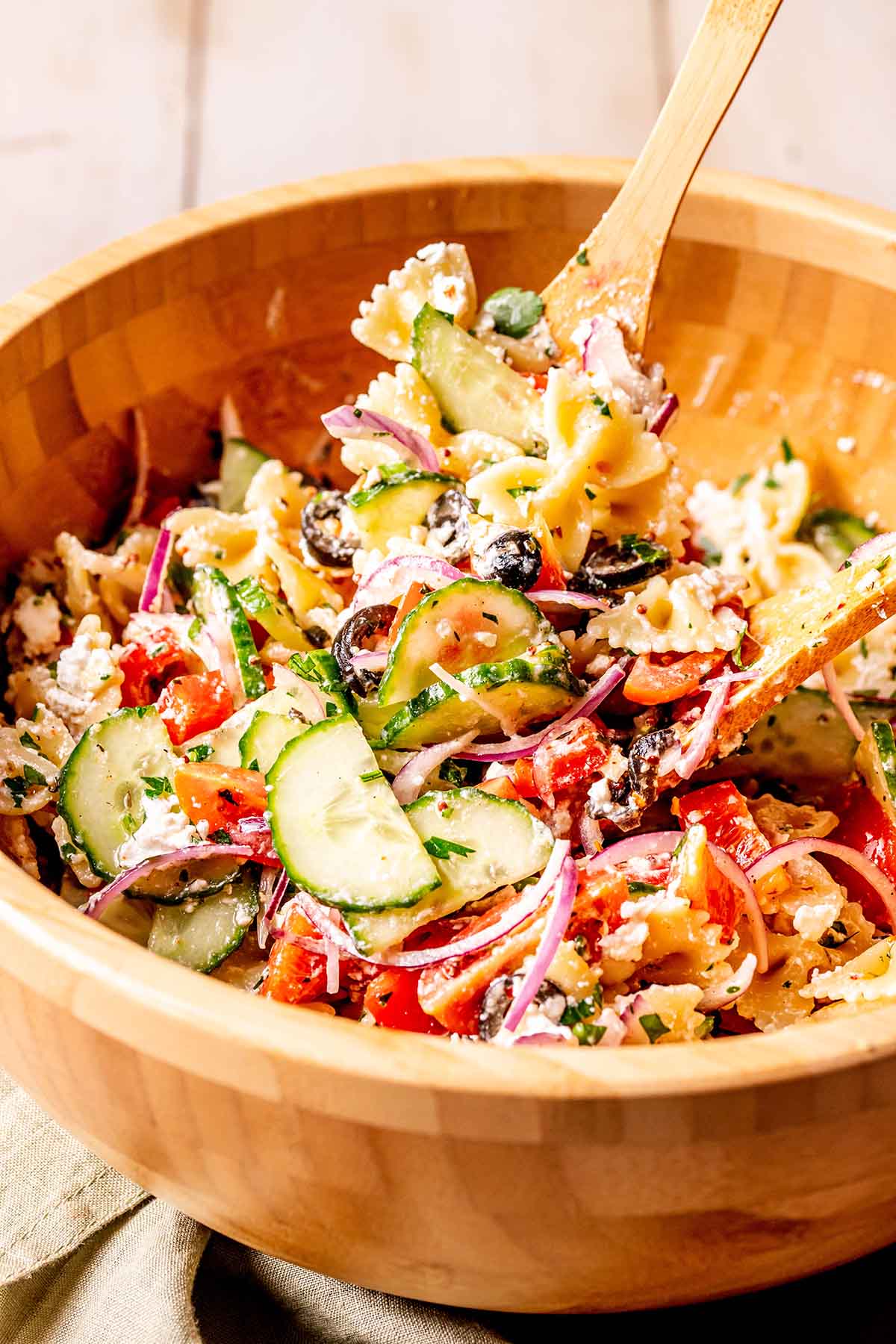 healthy pasta salad in a wooden bowl with a wooden serving spoon.