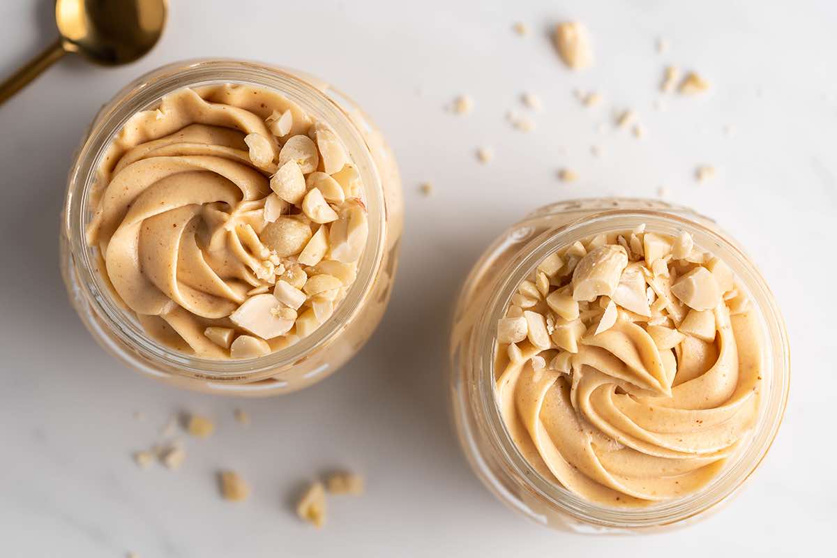 two jars of peanut butter mousse with peanuts on top.