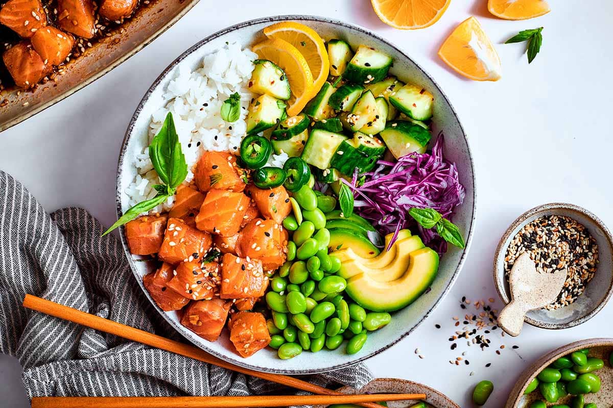 assembled salmon poke bowl with pickled cucumber, edamame, sliced avocado, ad purple cabbage.