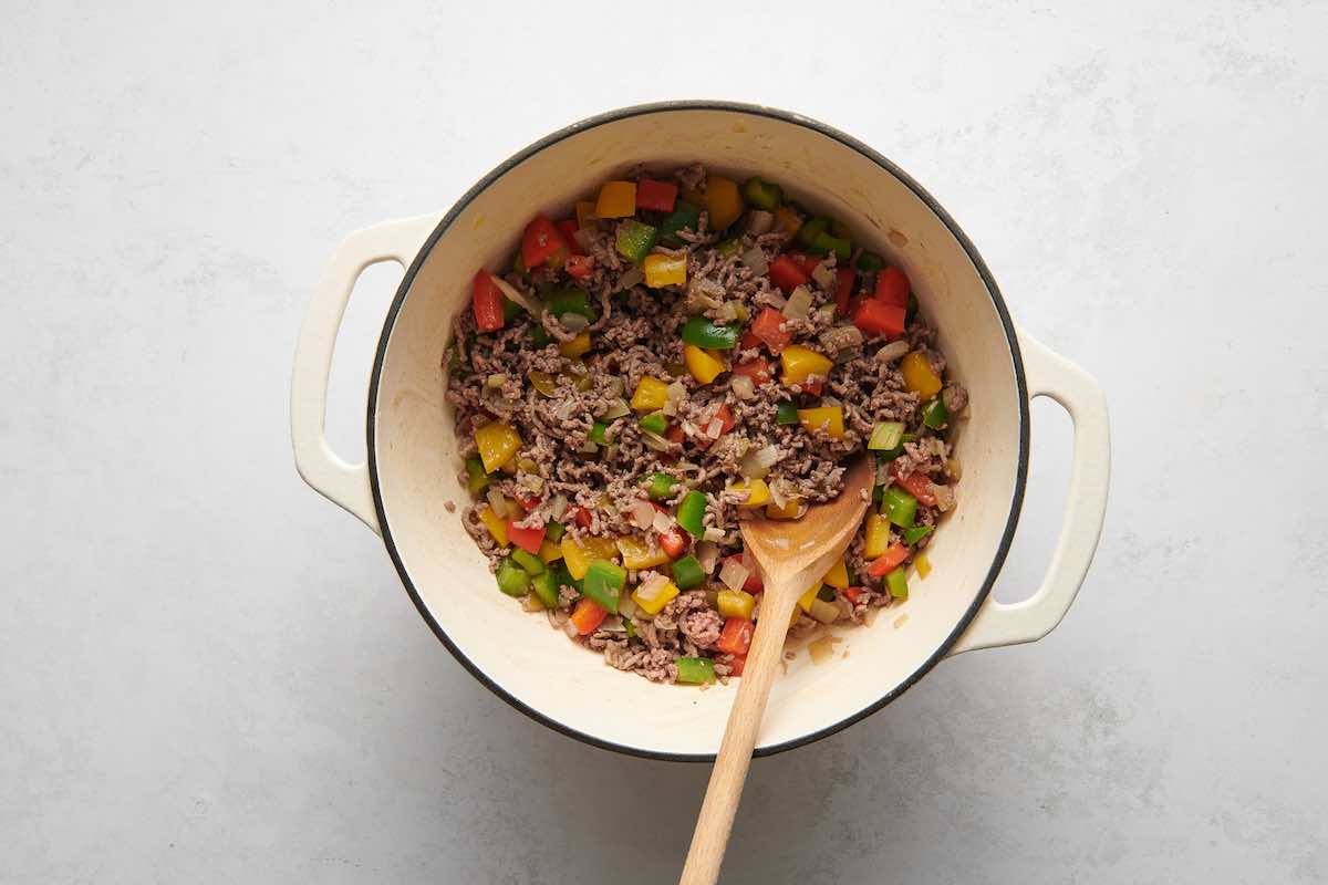 ground beef, bell peppers, and onion cooking in a pot.