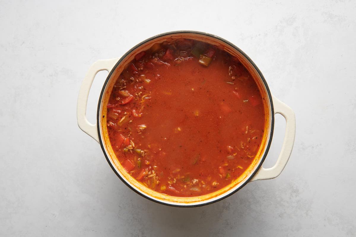 adding broth and tomatoes to soup pot.