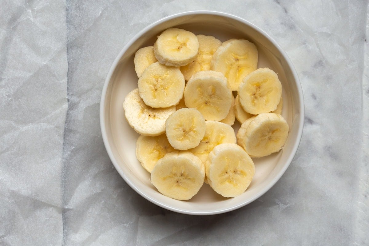 sliced bananas in a bowl with olive oil.