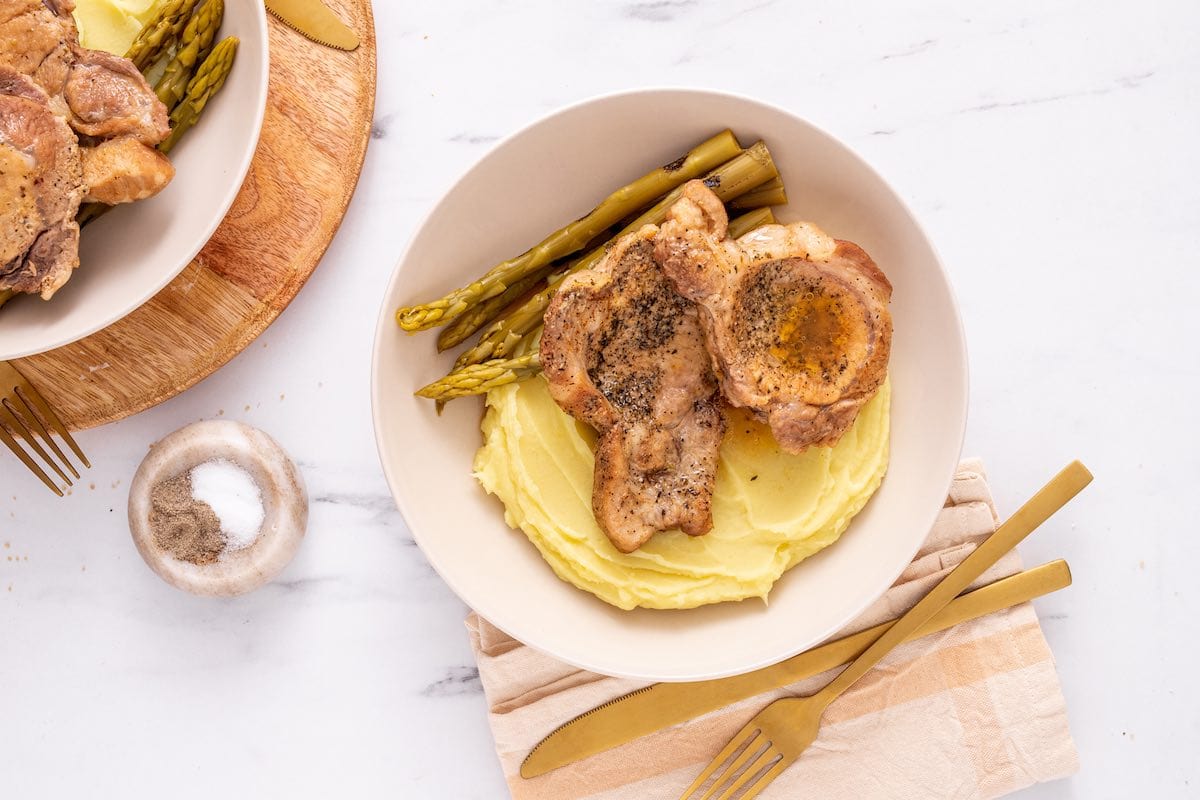 instant pot pork chops in a bowl with asparagus and mashed potatoes.