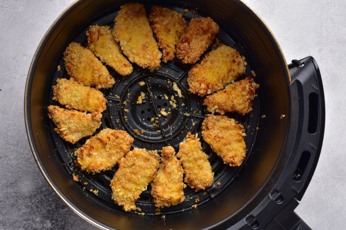 chicken nuggets half cooked in the air fryer basket.