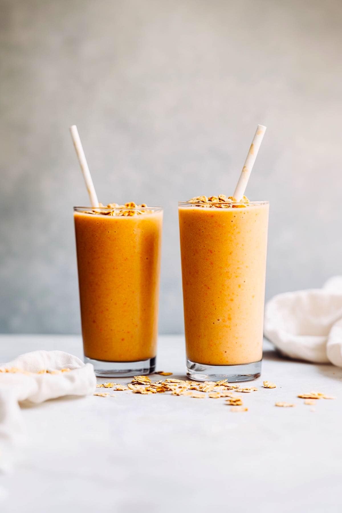 carrot smoothies in glasses with straws.