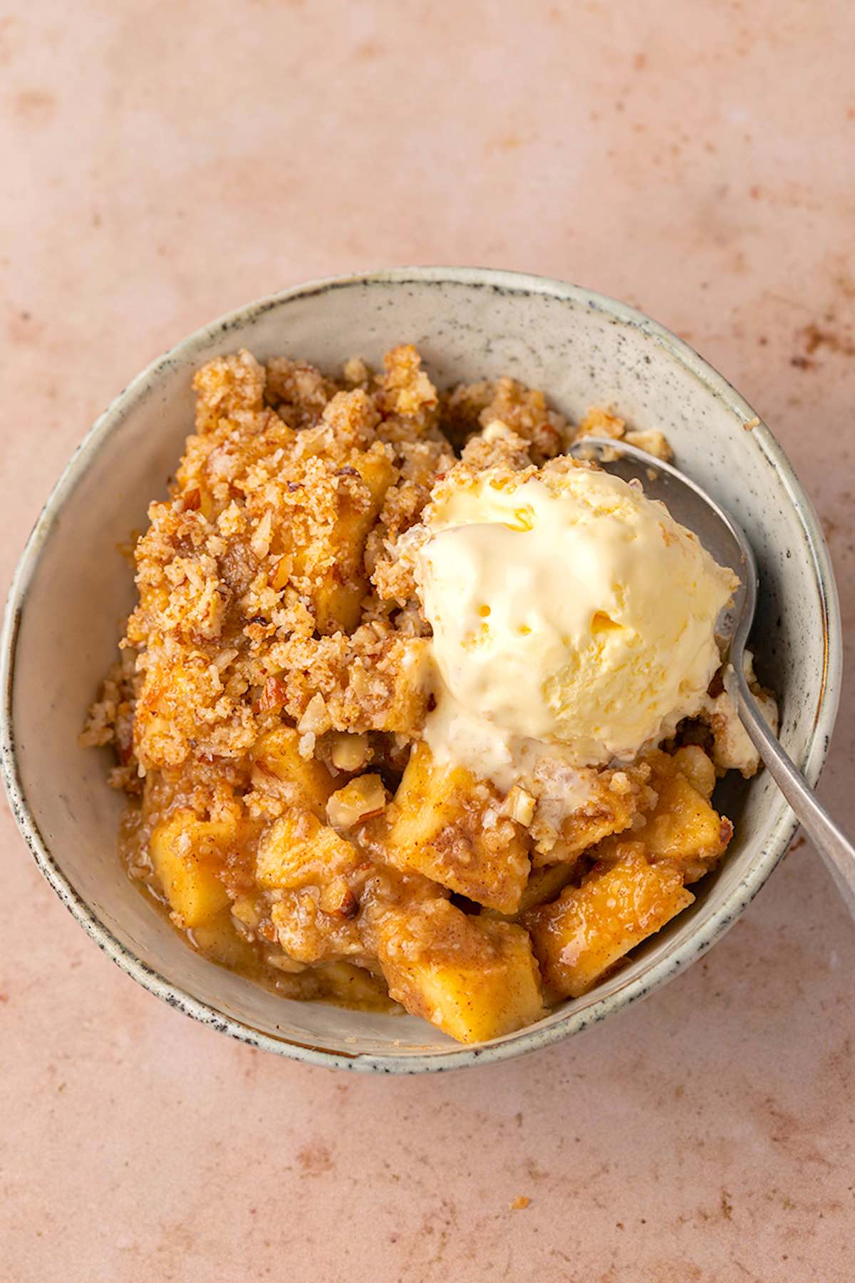 bowl of healthy apple crisp with a scoop of vanilla ice cream.