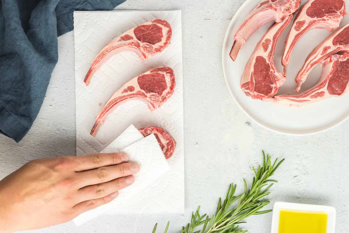 patting dry raw lamb chops.