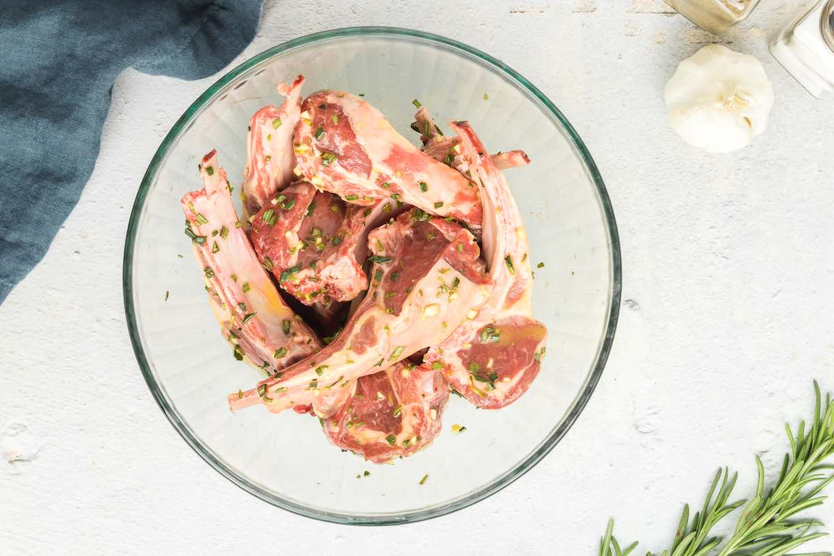 lamb chops in a mixing bowl with seasonings.