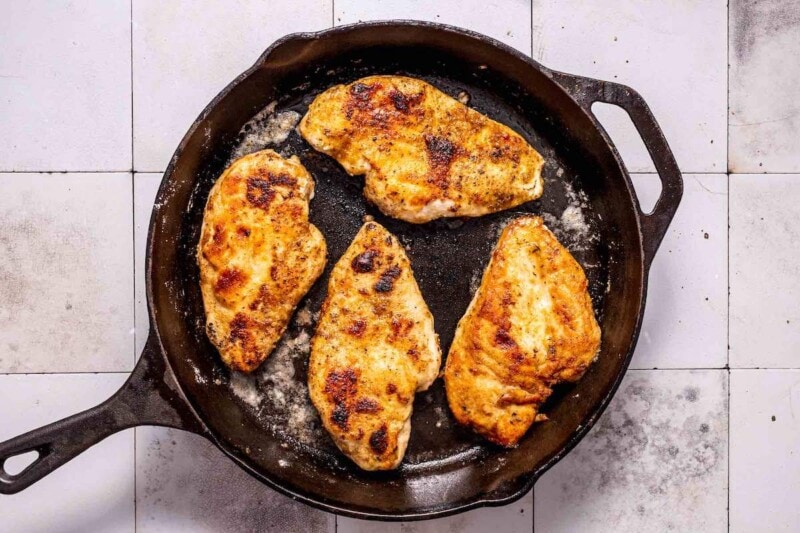 chicken breasts cooking in a skillet.