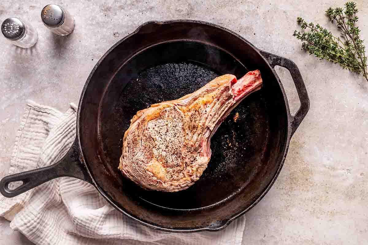 seared cowboy steak in skillet.