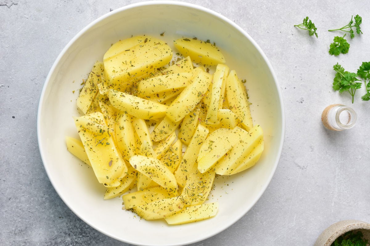 seasoned sliced potatoes in a bowl.