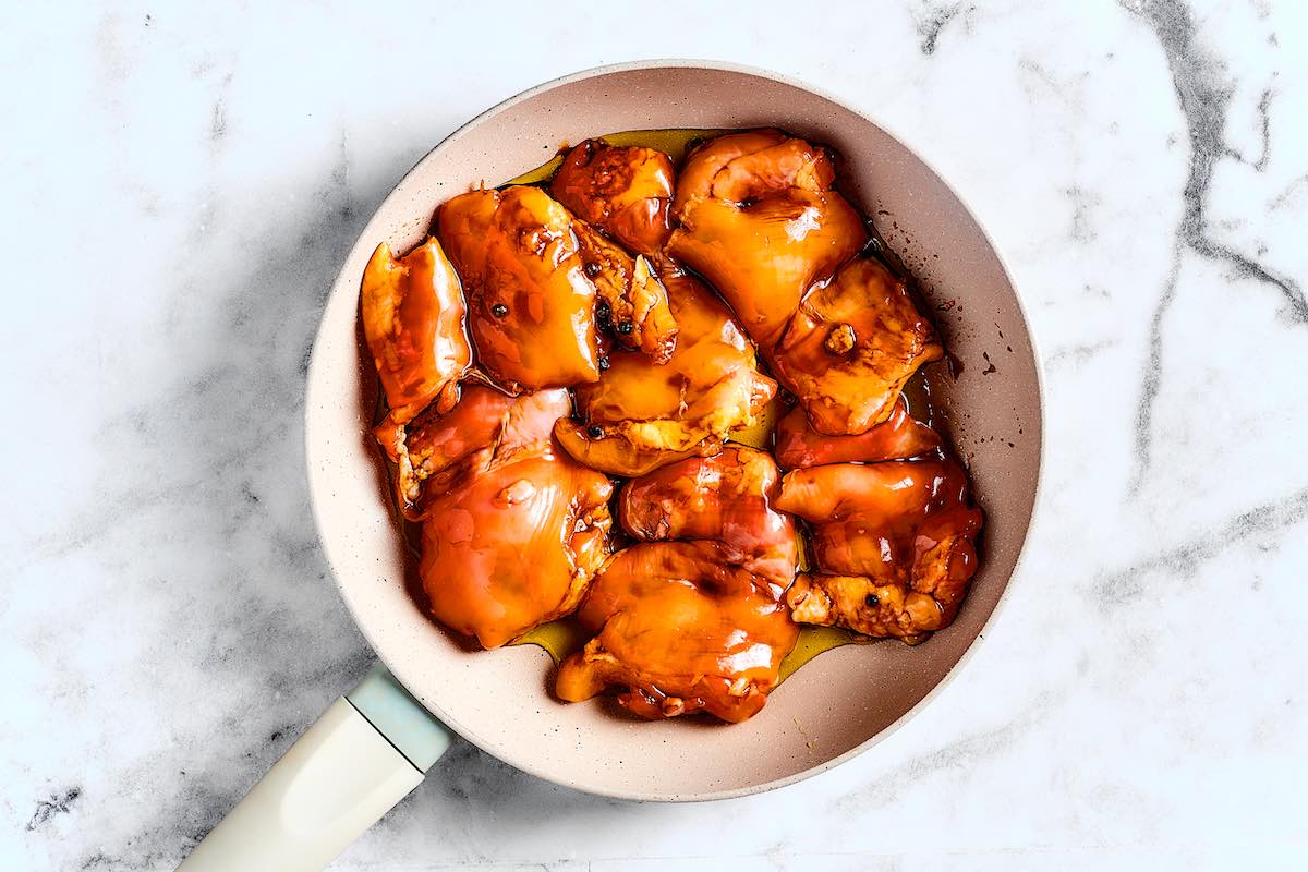 cooking the marinating chicken in a pan.